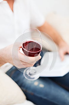 Male hand holdind book and glass of red wine