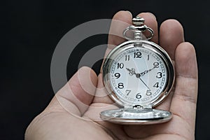 Male hand holding antique pocket watch.