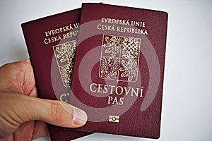 Male hand holding back of Czech passports as a symbol of international traveling and personal identification of European citiz