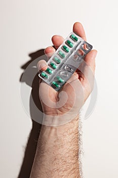 Male hand holding blister pack with green capsules