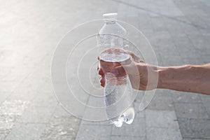 Male hand holding a bottle of water outdor