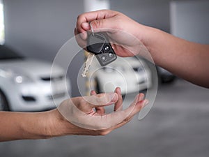 Male hand holding a car key and handing it over to another person