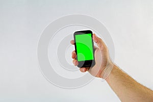 Male hand holding cell phone on white background with green scre