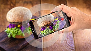 Male hand holding cellphone black smartphone making video of food, hamburger being filmed for website or delivery app