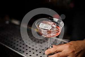 Male hand holding a cocktail glass with alcoholic drink