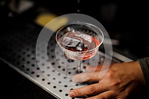 Male hand holding a cocktail glass with sweet alcoholic drink