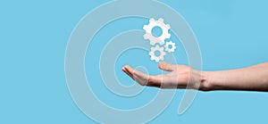 Male hand holding cog gears icon ,mechanism icon on virtual screens on blue background. Automation Software Technology Process
