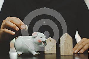 Male hand holding a coin in a white pig piggy bank. Business concepts, finance, savings, taxes and retirement investments