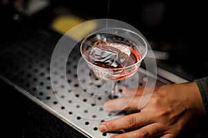 Male hand holding an elegant cocktail glass with sweet alcoholic drink