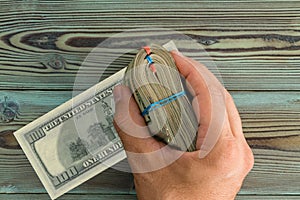 Male hand holding a folded bundle of 100 USD notes