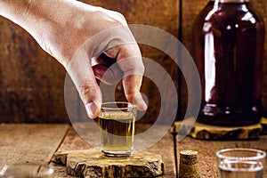 Male hand holding a glass of distilled alcoholic beverage, called