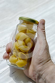 Male hand is holding glass jar of dry Conchiglie