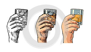 Male hand holding a glass with whiskey and ice cubes.