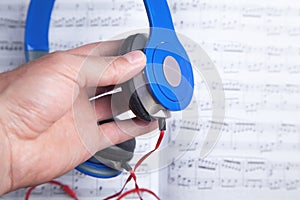 Male hand holding headphones on book of music note