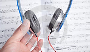 Male hand holding headphones on book of music note