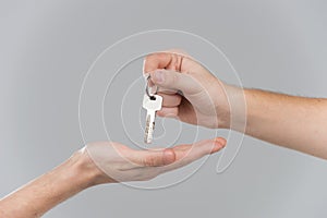 Male hand holding key and handing it over to another person.