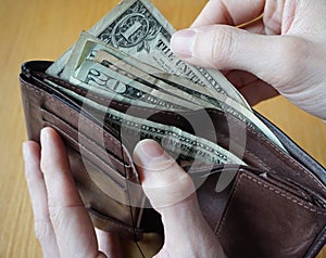 Male hand holding a leather wallet and withdrawing American currency (USD, US Dollars) photo