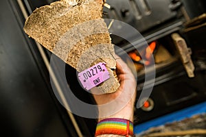 Male hand holding marked firewood for burning ready to insert it in black