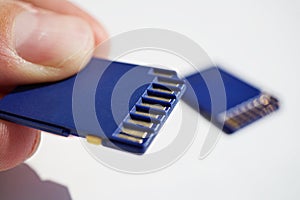 Male hand holding a memory card (SD card - Secure Digital card) used in video cameras and computers in blue color