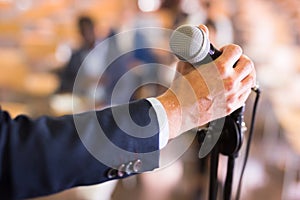 Male hand holding microphone at conference hall