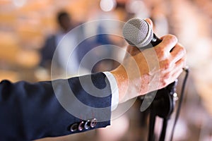 Male hand holding microphone at conference hall
