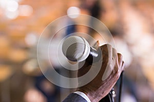 Male hand holding microphone at conference hall