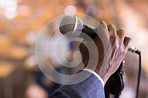 Male hand holding microphone at conference hall