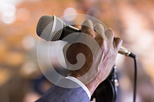 Male hand holding microphone at conference hall