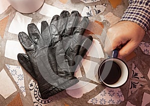 Male hand holding mug of espresso coffee on the table
