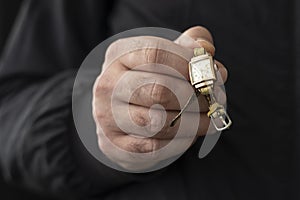 Male hand holding an old gold wristwatch.