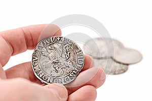 Male hand holding old silver thaler with lion on reverse. Old coins on white background. Lion Daalder. Selective focus