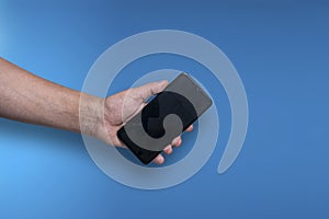 Male hand holding a phone on a blue background