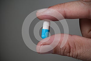 Male hand holding pill.