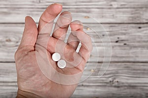 Male hand holding pills on wooden background with copy space