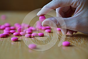 Male hand holding a pink pill as a symbol of pharmacy