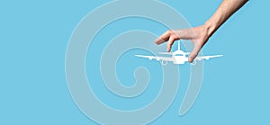 Male hand holding plane airplane icon on blue background. Banner.nline ticket purchase.Travel icons about travel planning,