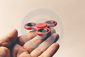 Male hand holding popular red Fidget Spinner toy on fingers