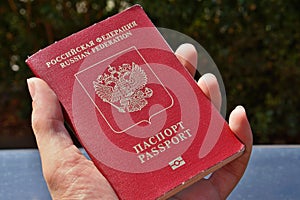 Male hand holding a Russian passport with captions Passport and Russian Federation in Cyrillic alphabet