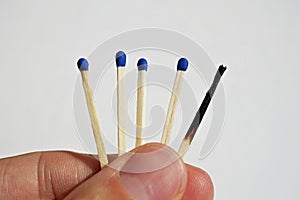 Male hand holding safety matches, one with with already burnt top and other unburnt fresh one as a symbol of contrast and choice photo