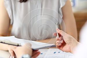 Male hand holding silver pen offering some papers for approval terms of cooperation pact