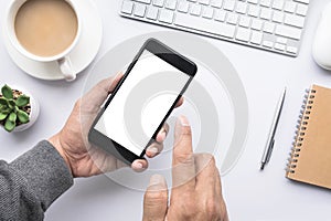 Male hand holding smartphone on office desk table