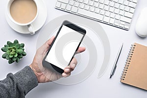 Male hand holding smartphone on office desk table