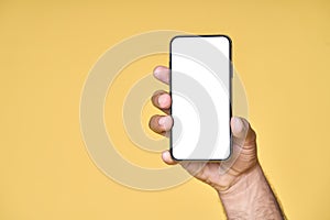 Male hand holding smartphone with white screen isolated on yellow background.