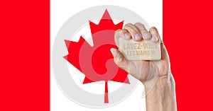 Male hand holding soap with words: Lavez-vous les mains and Canadian flag behind