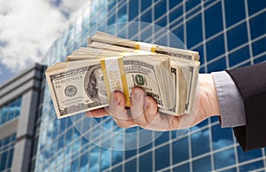 Male Hand Holding Stack of Cash with Corporate Building