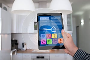 Male hand holding tablet app smart home kitchen in house