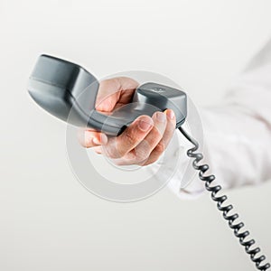 Male hand holding telephone handset towards you