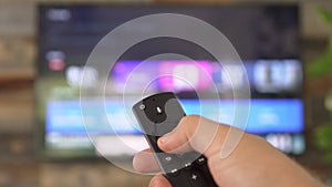 Male hand holding the TV remote control and changing TV channels