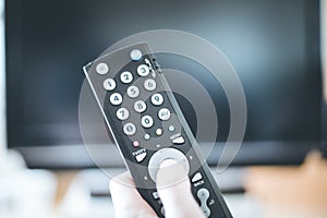 Male hand is holding TV remote control, smart TV