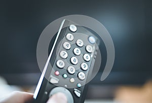 Male hand is holding TV remote control, smart TV